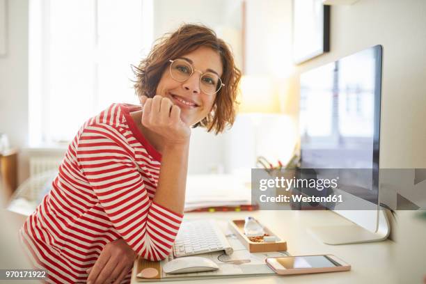 portrait of content mature woman sitting at desk at home - woman white shirt stock-fotos und bilder