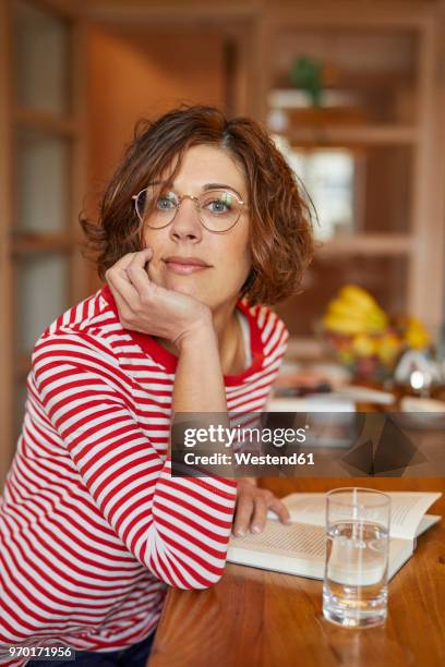 portrait of mature woman with book at home - water glasses ストックフォトと画像