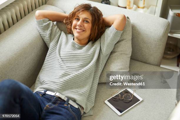 portrait of smiling mature woman relaxing on couch - hands behind head stock pictures, royalty-free photos & images