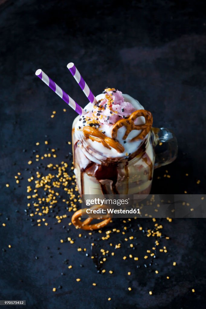 Glass of vanilla milkshake with cacao, chocolate sauce, whipped cream and topping
