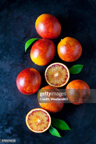 whole and sliced blood oranges on dark ground - blood orange stock pictures, royalty-free photos & images