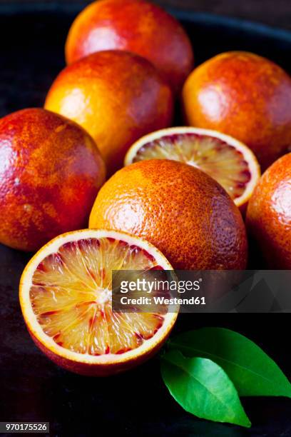 whole and sliced blood oranges, close-up - bloedsinaasappel stockfoto's en -beelden