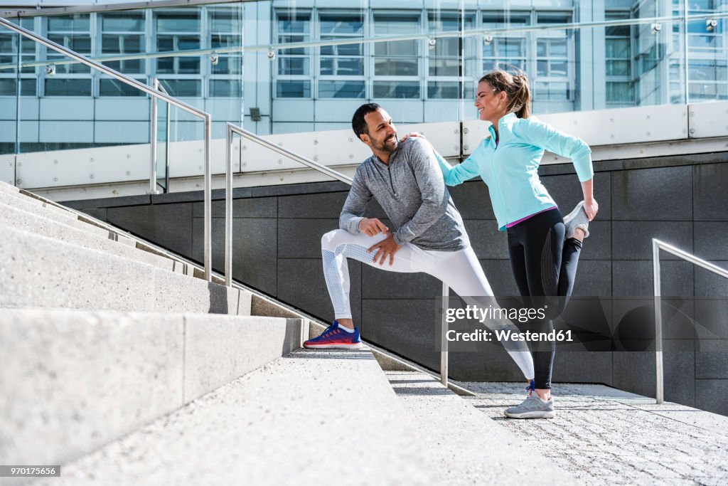 Couple doing stretching exercise on stairs in the city
