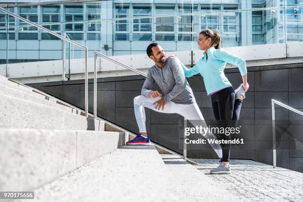 couple doing stretching exercise on stairs in the city - active couple stock-fotos und bilder