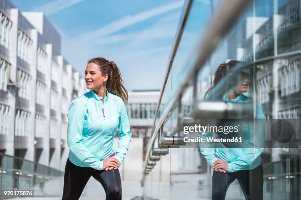 young woman doing stretching exercise in the city - turn fotografías e imágenes de stock