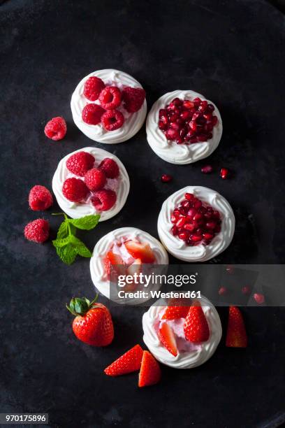 meringue pastries garnished with whipped cream, berries and pomegranate seed - strawberry and cream stock-fotos und bilder