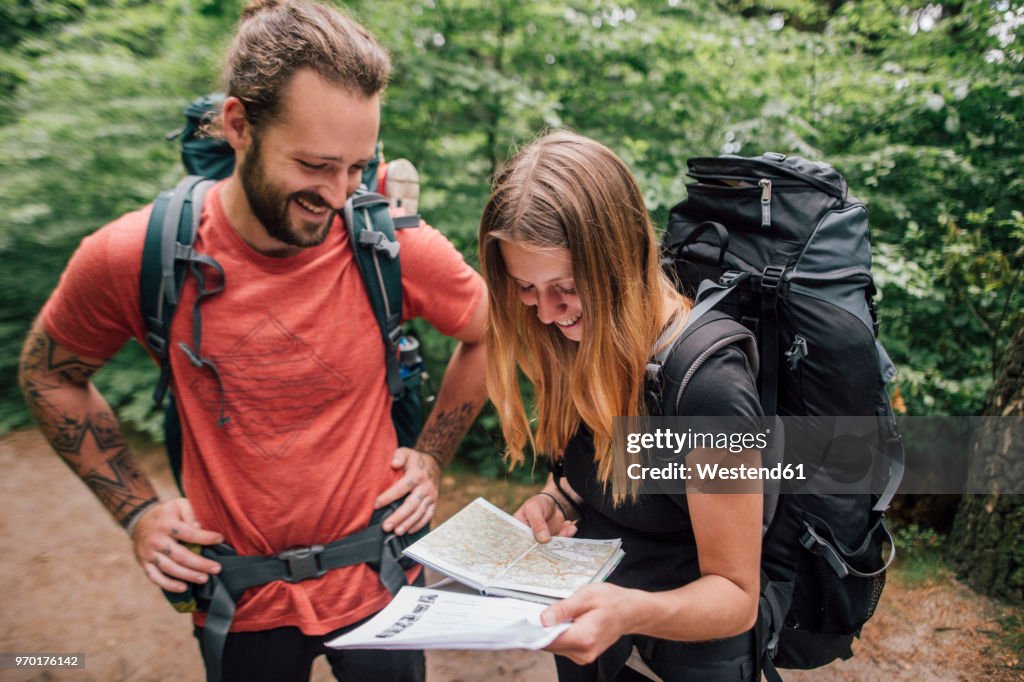 Happy young couple on a hiking trip reading map