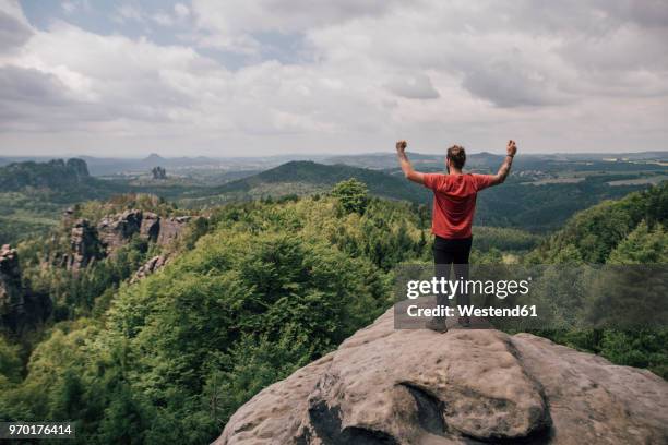 germany, saxony, elbe sandstone mountains, man on a hiking trip standing on rock cheering - saxony stock-fotos und bilder