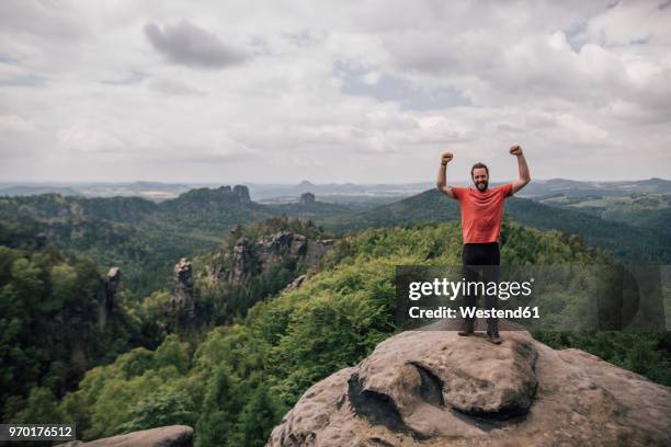 germany, saxony, elbe sandstone mountains, man on a hiking trip standing on rock cheering - mann ganzkörper lachen stehen stock-fotos und bilder