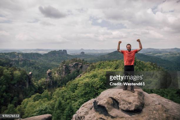 germany, saxony, elbe sandstone mountains, man on a hiking trip standing on rock cheering - saxony stockfoto's en -beelden