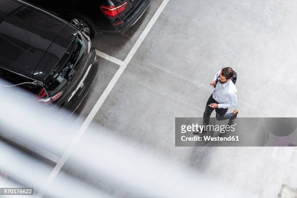 young businessman with backpack on the go at parking garage - business man walk stockfoto's en -beelden