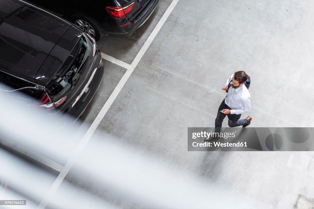 Young businessman with backpack on the go at parking garage