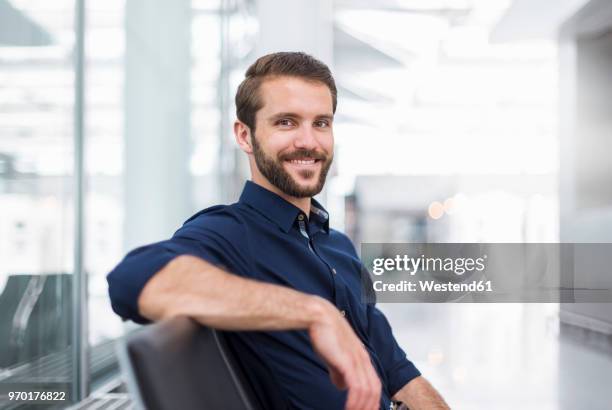 portrait of smiling young businessman sitting in waiting area - manga dobrada - fotografias e filmes do acervo