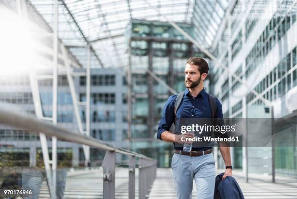 young businessman on the go at building with glass facade - glass business man stock-fotos und bilder