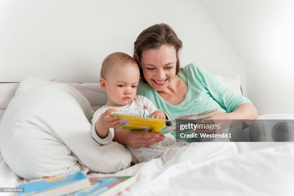 Mother and baby in bed reading picture book