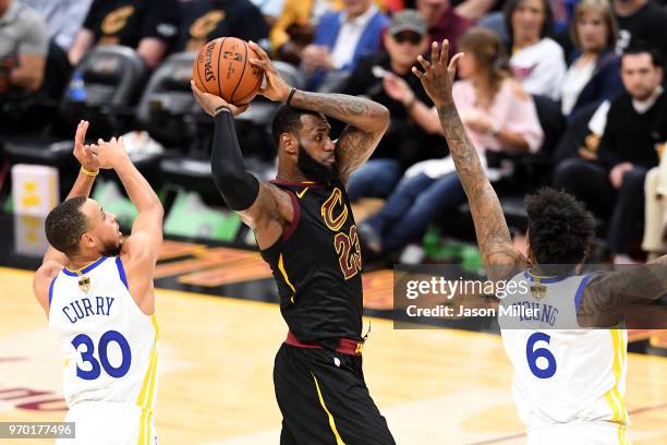 LeBron James of the Cleveland Cavaliers handles the ball against Stephen Curry and Nick Young of the Golden State Warriors in the first half during...