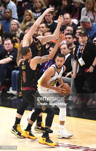Stephen Curry of the Golden State Warriors handles the ball against George Hill and Kevin Love of the Cleveland Cavaliers in the first half during...