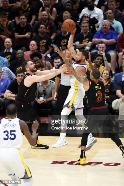 Stephen Curry of the Golden State Warriors handles the ball against Kevin Love and George Hill of the Cleveland Cavaliers in Game Four of the 2018...