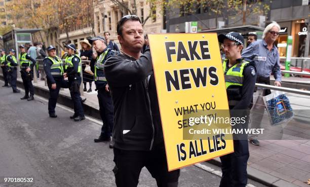 Man holds up a 'Fake News' placard as members of the Australian Liberty Alliance and supporters protest outside the British consulate in support of...