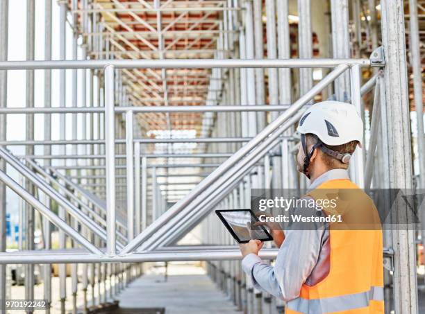 architect with tablet wearing hard hat on construction site - worker inspecting steel stock pictures, royalty-free photos & images