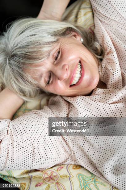 happy mature woman lying down relaxing - down blouse imagens e fotografias de stock