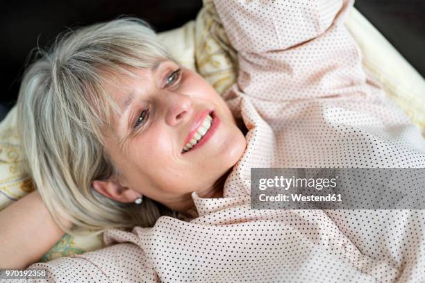 happy mature woman lying down relaxing - down blouse imagens e fotografias de stock