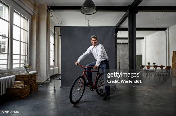 portrait of mature businessman on fixie bike in front of black backdrop in loft - black shirt 個照片及圖片檔