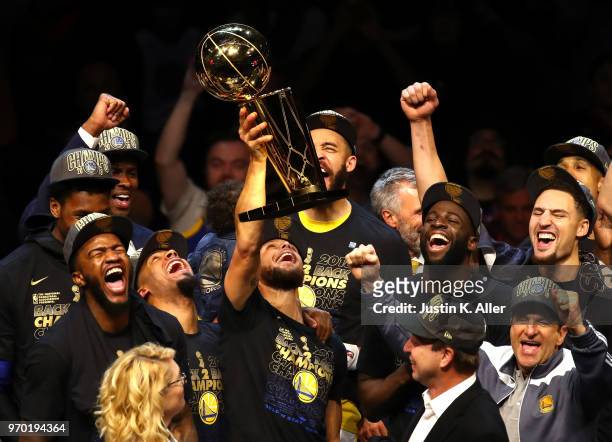 Stephen Curry of the Golden State Warriors celebrates with the Larry O'Brien Trophy after defeating the Cleveland Cavaliers during Game Four of the...