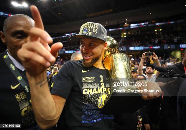 Stephen Curry of the Golden State Warriors celebrates with the Larry O'Brien Trophy after defeating the Cleveland Cavaliers during Game Four of the...