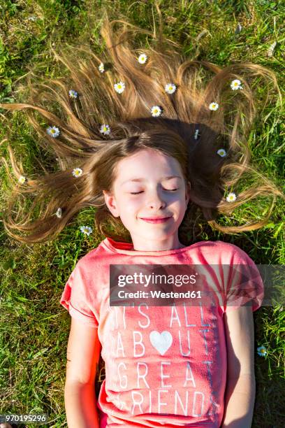 portrait of smiling girl lying on grass in spring with daisies on hair - happy tween girls lying on grass stock pictures, royalty-free photos & images