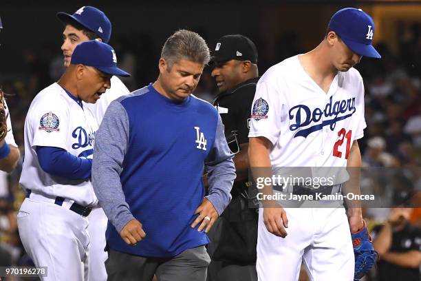 Heat athletic trainer Neil Rampe walks off the field with starting pitcher Walker Buehler of the Los Angeles Dodgers as he leaves because of an...