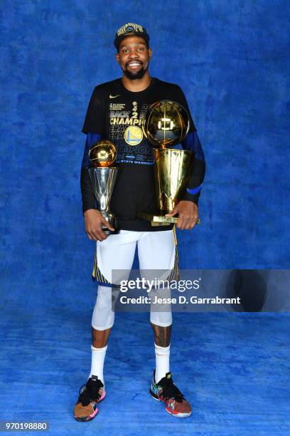Kevin Durant of the Golden State Warriors poses for a portrait with the Larry O'Brien Championship trophy and the Bill Russell Finals MVP trophy...