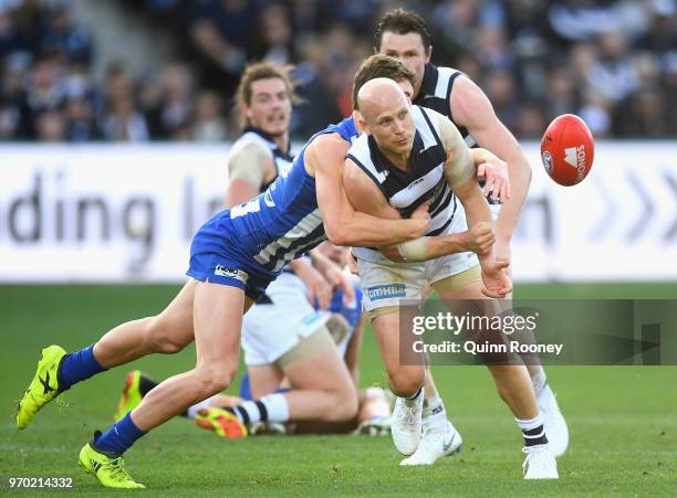 Gary Ablett of the Cats handballs whilst being tackled by Tom Murphy of the Kangaroos during the round 12 AFL match between the Geelong Cats and the...