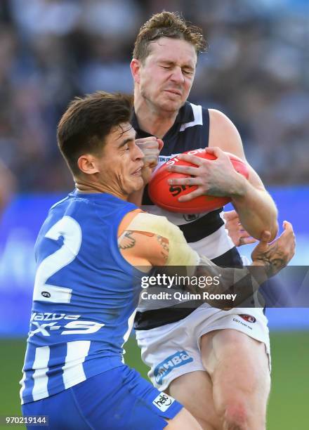 Mitch Duncan of the Cats is tackled by Marley Williams of the Kangaroos during the round 12 AFL match between the Geelong Cats and the North...