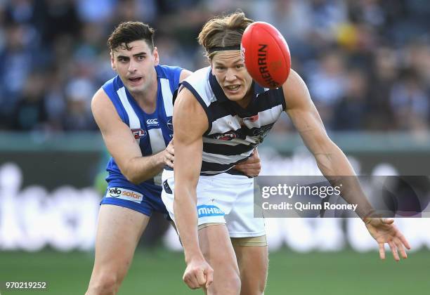Rhys Stanley of the Cats handballs whilst being tackled by Paul Ahern of the Kangaroos during the round 12 AFL match between the Geelong Cats and the...