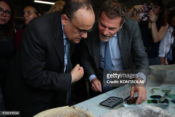 The Italian Minister of Culture Alberto Bonisoli with director Massimo Osanna looks at pottery and coins found in the work site of new excavations in...