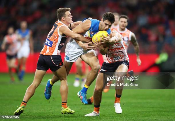 Jack Leslie of the Suns is challenged by Zac Langdon and Jonathon Patton of the Giants during the round 12 AFL match between the Greater Western...