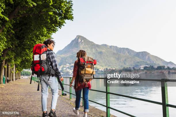 young backpackers walking on the lakeside - lake como road stock pictures, royalty-free photos & images