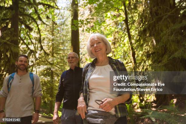 senior couple and son hiking in forest - pulsante di apertura o di chiusura foto e immagini stock