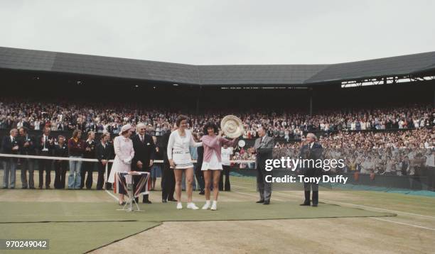 Queen Elizabeth II looks on as Virginia Wade of Great Britain holds aloft the Venus Rosewater Dish after defeating Betty Stove in their Women's...