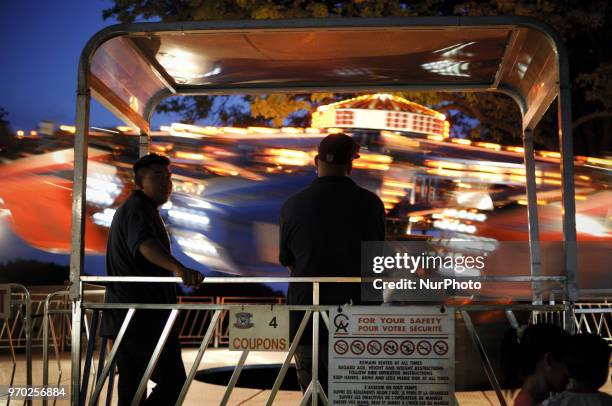 To workers supervise a ride in progress at a small community carnaval, in Wyndmoor, PA, just outside Philadelphia, on June 8, 2018.