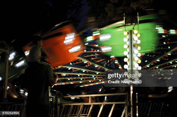 Child sits on the neck of a man as watch a ride a small community carnaval, in Wyndmoor, PA, just outside Philadelphia, on June 8, 2018.