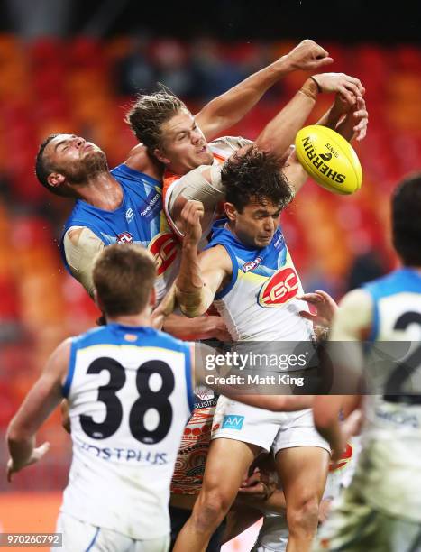 Harrison Himmelberg of the Giants is challenged by Jarrod Witts and Jarrod Harbrow of the Suns during the round 12 AFL match between the Greater...