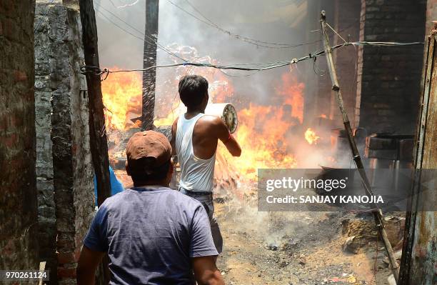 Indian residents try to extinguish a fire at a vermicelli factory in the old city in Allahabad on June 9, 2018.