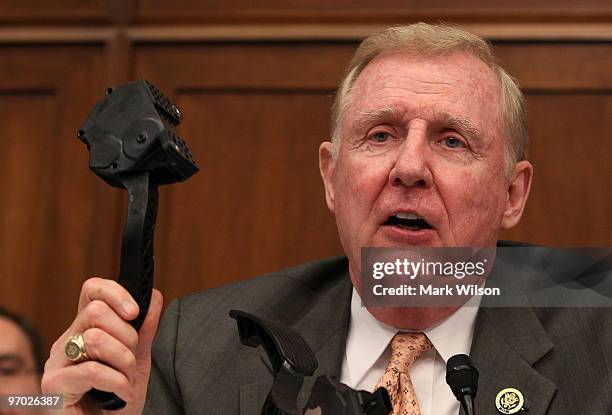 Rep. Dan Burton holds up an accelerator pedal while questioning Toyota Motor Corporation President and CEO Akio Toyoda during his appearance before...