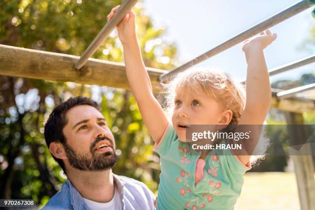 padre mirando hija escalada barras - monkey bars fotografías e imágenes de stock