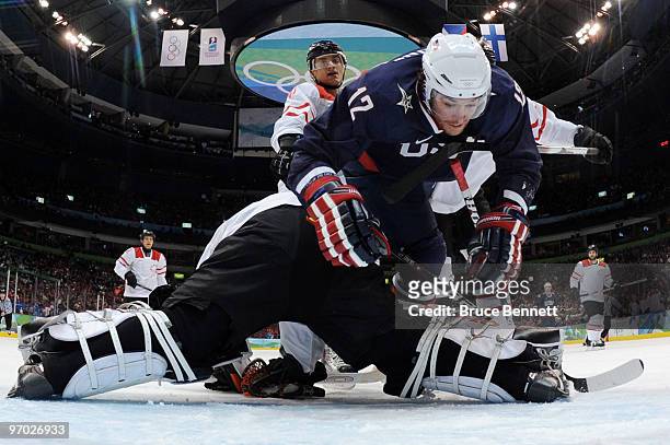 Ryan Malone of the United States falls over goal tender Jonas Hiller of Switzerland in the first period during the ice hockey men's quarter final...