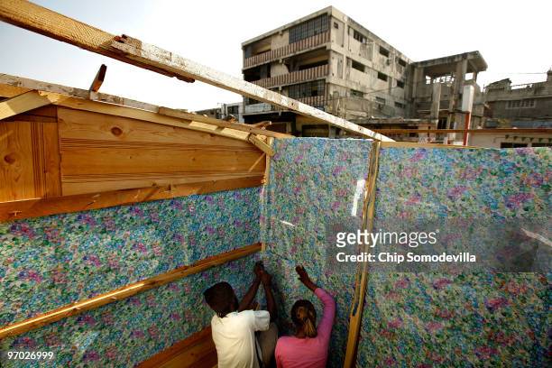 Pierre-Toussaint Glanys and Claudette Clement use gift wrapping paper to wallpaper the inside of the shack they have built where the collapsed Marche...