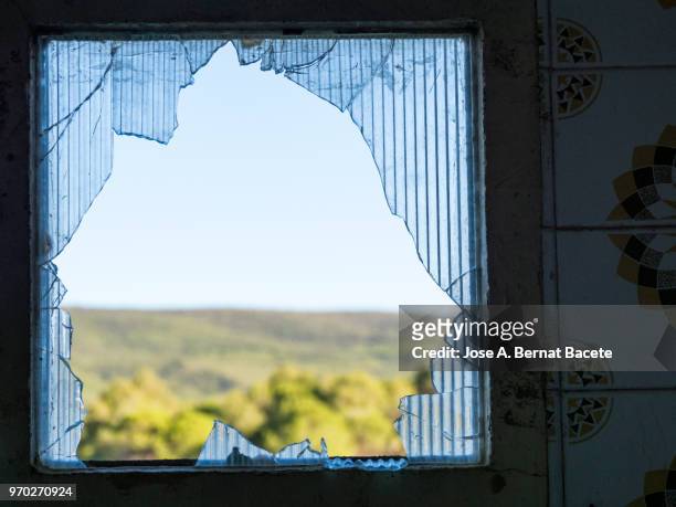 close-up of abandoned window  of a house with the glasses broken with a view to the field. - breaking window stockfoto's en -beelden