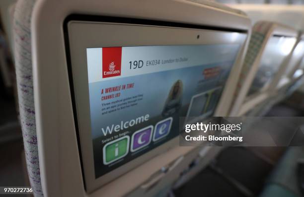 Inflight entertainment screens sit on the back of chairs in the economy class cabin on board a Boeing Co. 777-300ER passenger jetliner, operated by...